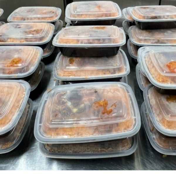 Numerous African cuisine takeout containers filled with food, stacked on a metal surface.