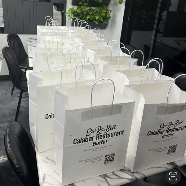 Numerous white Sarabell Calabar Restaurant takeout bags with handles are neatly arranged on a marble counter.