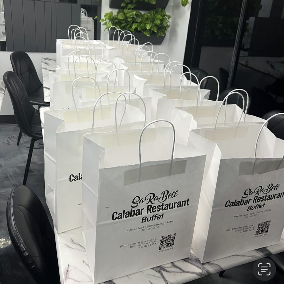 Numerous white Sarabell Calabar Restaurant takeout bags with handles are neatly arranged on a marble counter.